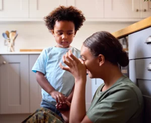 Military Mom Stressed out on the kitchen floor with son comforting